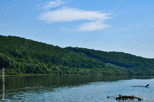 Riverscape on a summer day with Oka river, forest growing on a river bank and cloudy sky