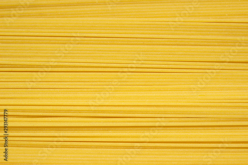 Thin pasta arranged in rows. Yellow italian pasta. Long spaghetti. Raw spaghetti wallpaper. Food background concept.