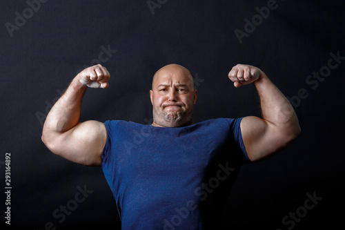A portrait of bald strongman in dark t-shirt