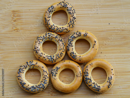 Photography of fresh delicious bread rings (bagels, sushki or baranki) with poppy seeds on the wooden background.