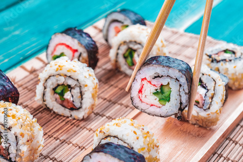 Sushi Rolls in a Row with Salmon, Rice and cucumber on Blue Wood background. White and Black Sushi, Sushi Rolls on Seaweed. Closeup of Delicious Japanese food with Sushi Roll.