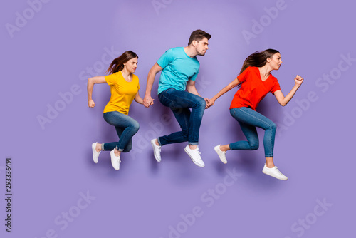 Full length size body photo of concentrated with funny facial expression group of three hipsters running away do not look back isolated violet background