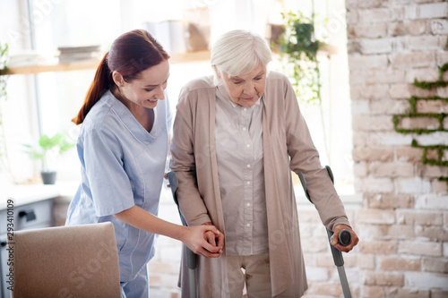 Helpful caregiver assisting woman with crutches