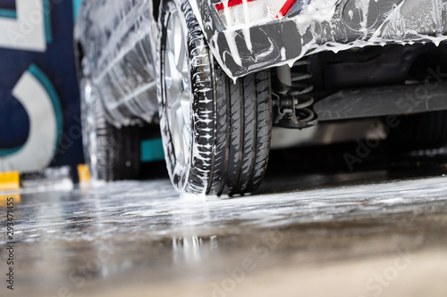 Close-up of manual car washing with pressurized water in car wash shop.
