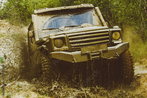 Mud and water splash in off-road racing. Offroad vehicle coming out of a mud hole hazard. Drag racing car burns rubber. Extreme. Off-road car. Rally racing.