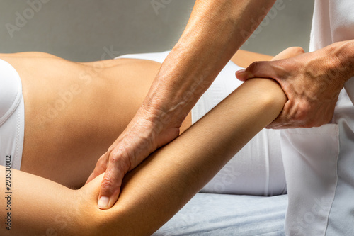 Physiotherapist applying pressure on female forearm muscle.