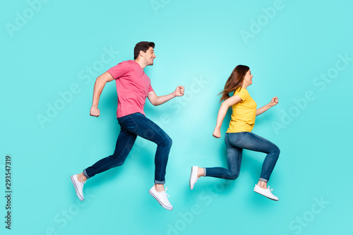 Full length body size profile side view of nice attractive funny cheerful couple running in air having fun isolated over bright vivid shine vibrant green turquoise background