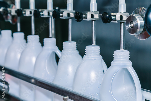 white plastic gallons or bottle on the production line of the conveyor at filling machine in the factory. selective focus. industrial and technology concept.