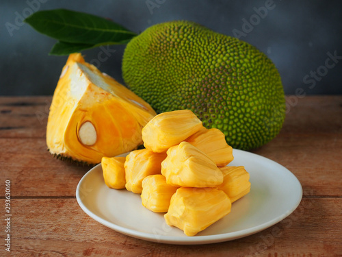 Ripe jackfruit flesh in a white plate on a wooden table for tropical fruit or meat substitute concept.