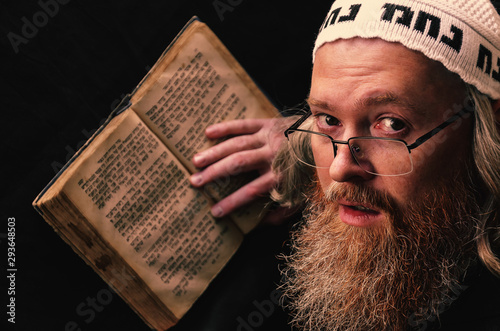 A Hasidic Jew reads Siddur. Religious orthodox Jew with a red beard and with pace in a white bale praying. On the bale is an inscription Rabbi Nahman from Uman. Closeup