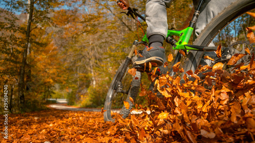 CLOSE UP: Unrecognizable man rides mountain bike into a pile of fallen leaves