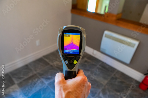 Indoor damp & air quality (IAQ) testing. A close up view on the rear screen of an infrared thermal vision camera, pointing towards the corner of a room with cold tiled floor and warm insulated walls.