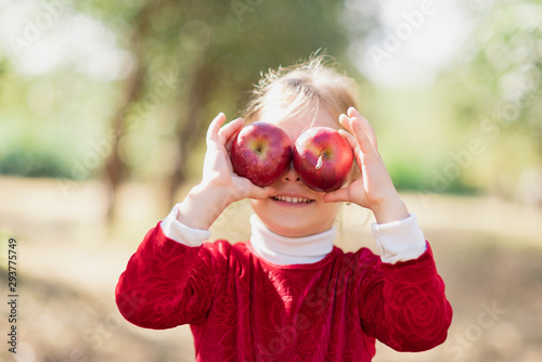 Girl with Apple holding in front of her face in Orchard. Harvest Concept.