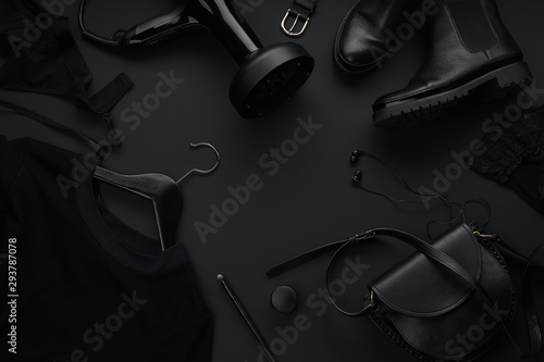 Black monochromatic flatlay on black background. Clothes, accessories and beauty equipment. Black friday sale concept