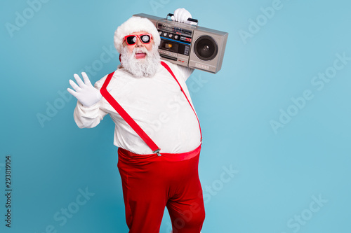 Portrait of nice bearded cheerful funky funny glad big belly Santa carrying tape player having fun isolated over bright vivid shine vibrant blue turquoise color background