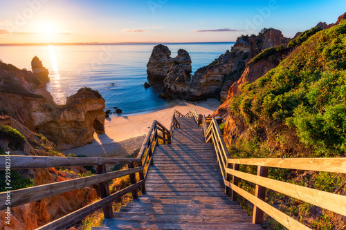 Sunrise at Camilo beach in Lagos, Algarve, Portugal. Wooden footbridge to the beach Praia do Camilo, Portugal. Picturesque view of Praia do Camilo beach in Lagos, Algarve region, Portugal.