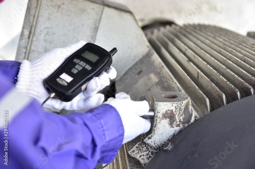 Inspector using a Handheld Vibration Tester for checking bearings and overall vibration of motor. Selective focus on inspection area.