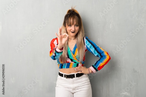 Young girl with colorful clothes showing an ok sign with fingers