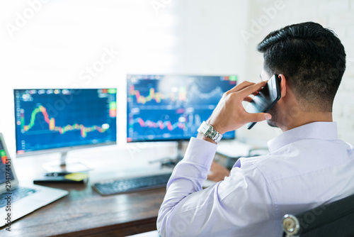 Young Male Stock Broker Using Computer For Buying Shares