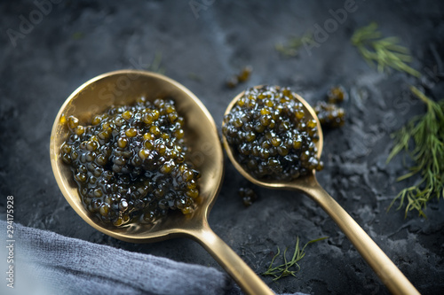Black Caviar in a spoon on dark background. High quality real natural sturgeon black caviar close-up. Delicatessen. Texture of expensive luxury caviar. Food Backdrop. Top view, flatlay