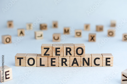 Zero tolerance - words from wooden blocks with letters, severely punishing all unacceptable behaviour, zero tolerance concept, random letters around, white background