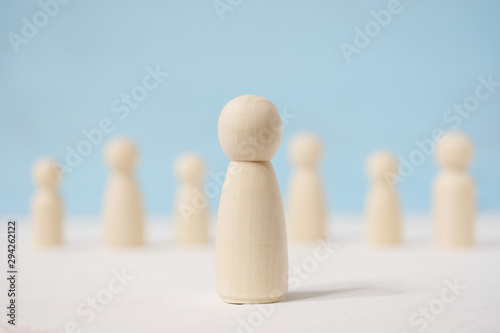 Wooden figures of man in the center and people stand apart from each other.