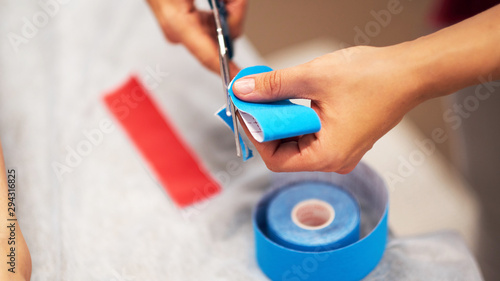oman massage therapist prepares kinesio tape cuts with scissors