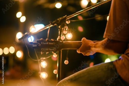 guitar, song, concert, music, musical, entertainment, musician, Rear view of the man sitting play acoustic guitar on the outdoor concert with a microphone stand in the front, musical concept.