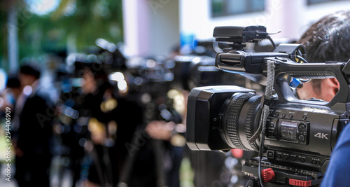 Press conference.Close-up of Video camera on blurred group of press and media photographer as background