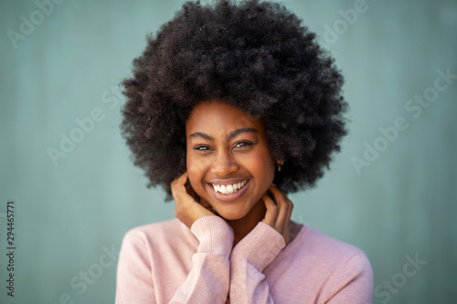 front portrait of attractive young african american woman with afro smiling and hand on face