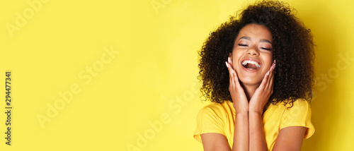 Super happy afro-american girl isolated on yellow background.