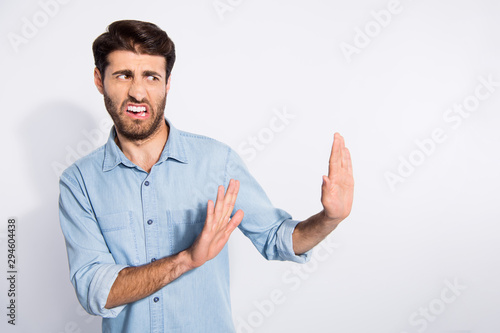 Photo of amazing multiethnic guy looking empty space with disgust stop with arms movement to him wear casual denim shirt isolated white color background