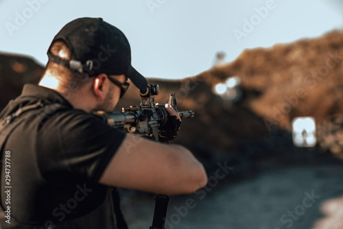 Close-up image of armed guy shooting at target outdoors.