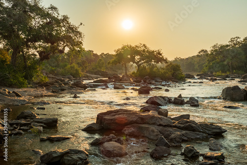 Sunset in Malawi river with trees and rocks