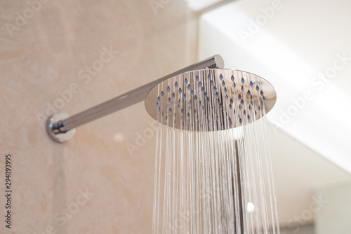 Shower turned on, overhead ceiling shower faucet head closeup.