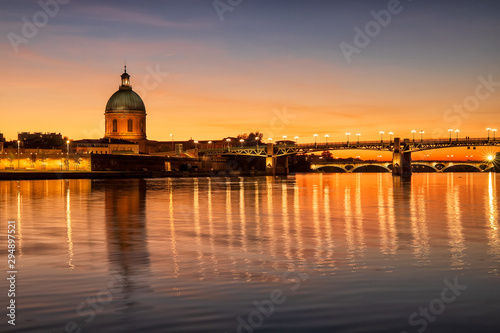 Golden sunset above Saint Joseph Chapel and Saint Pierre bridge. Light reflection in Garonne river. Long exposure photo. France. Europe