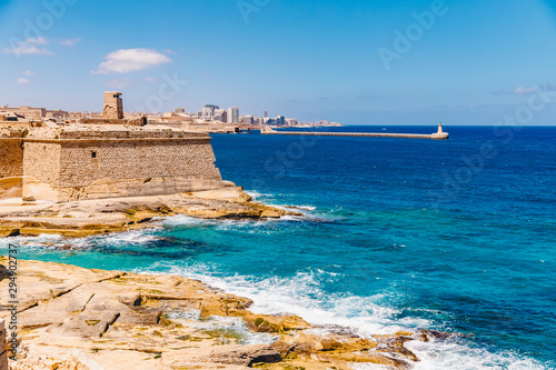 Ancient stone military fort Malta island made of brick rocks on shore blue sea with view city Valetta