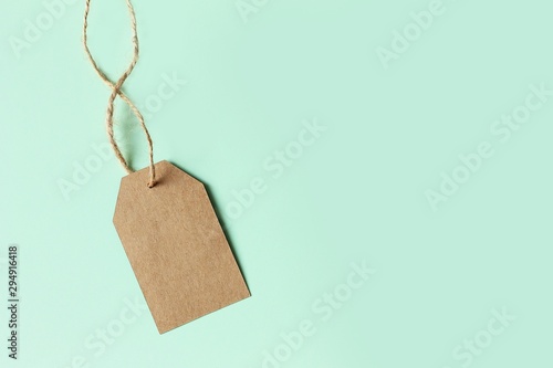 Brown cardboard price tag on pastel green background, top view. Sign sale.
