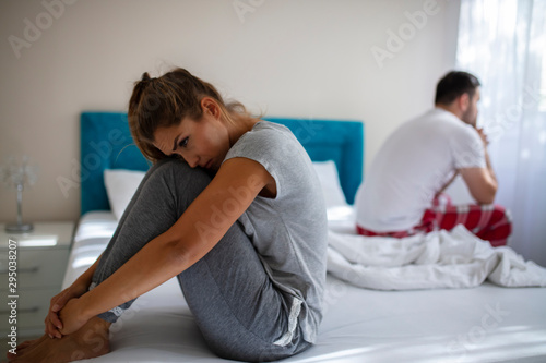 Blurred background of newlyweds have problems fighting in bed. Sleepy married couple have such serious health problem as erection & snoring. Wife is sulky & husband has erectile dysfunction.