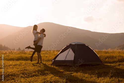 Figures of happy guy holding his girlfriend at sunset in autumn mountains camping