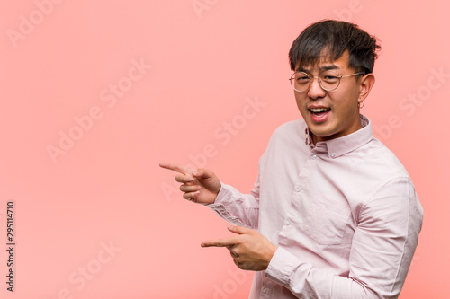 Young chinese man pointing to the side with finger