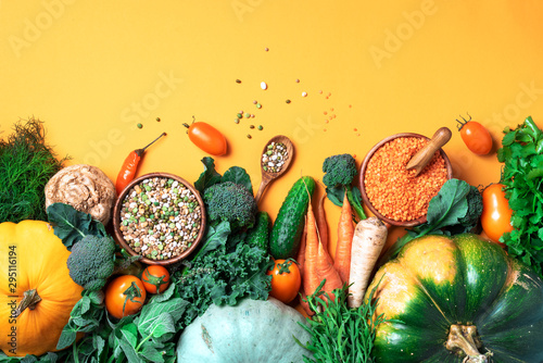 Organic vegetables, lentils, beans, raw ingredients for cooking on trendy yellow background. Healthy, clean eating concept. Vegan or gluten free diet. Copy space. Top view. Food frame