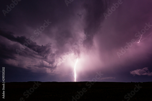 Powerful bolt of lightning striking the ground during thunderstorm.