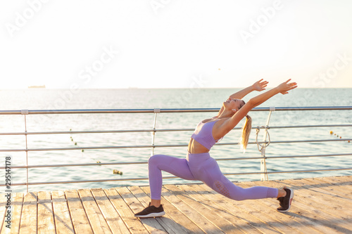 Practicing yoga. Training at sunrise. Young slim woman doing asana exercise on the beach. Healthy lifestyle concept