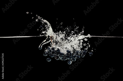 organic ripe blueberries falling in water with splash isolated on black