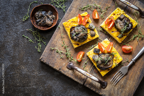 polenta corn with fried eggplant and mushrooms and cherry tomatoes on a dark background