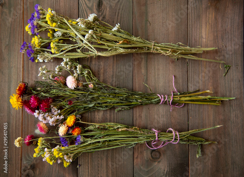 Three colorful bouquets of dried flowers on a wooden background.