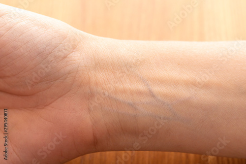 Human wrist with blue veins visible through skin close up