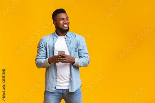 Handsome guy holding smartphone and looking aside at copy space