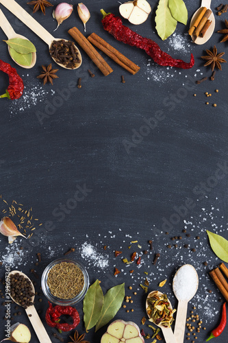 Colourful various herbs and spices and dry vegetable for cooking in wooden spoons and bowls on dark background with copy space. top view. vertical layout